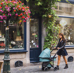 Woman in leather jacket pushing blue Greentom stroller 2 IN 1 in city.