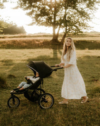 A mother pushing her baby in the Kinderkraft Stroller HELSI