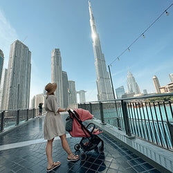 Woman with a Kinderkraft NUBI stroller on a bridge in Dubai, Burj Khalifa in the background.