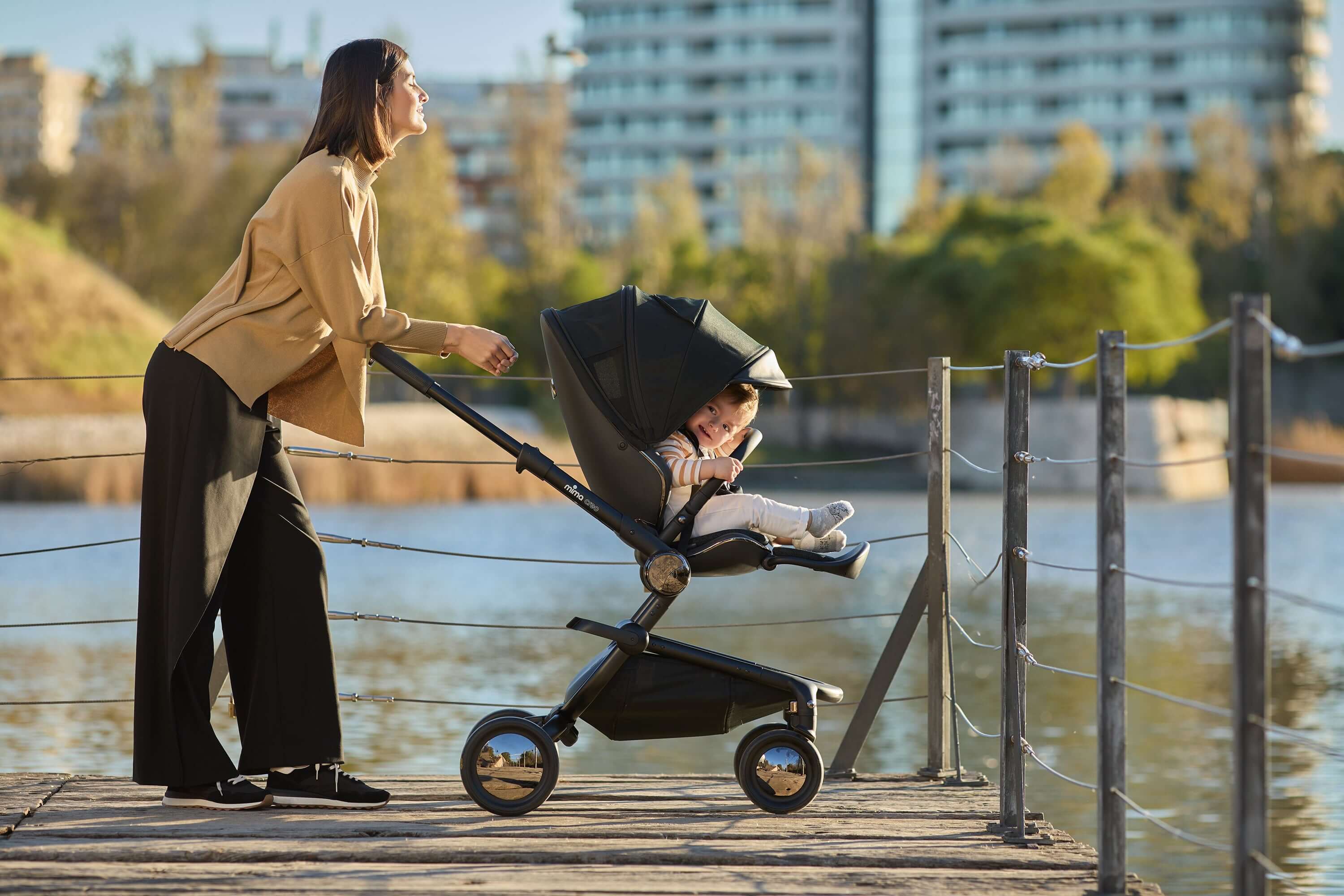 Mother and child enjoying the view by the lake with the Mima Creo Stroller Black.