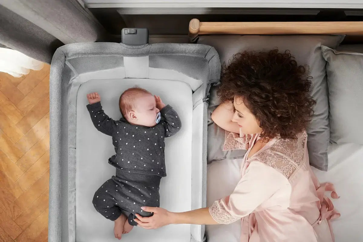 Top view of baby in polka dot outfit in Kinderkraft NESTE AIR Cot