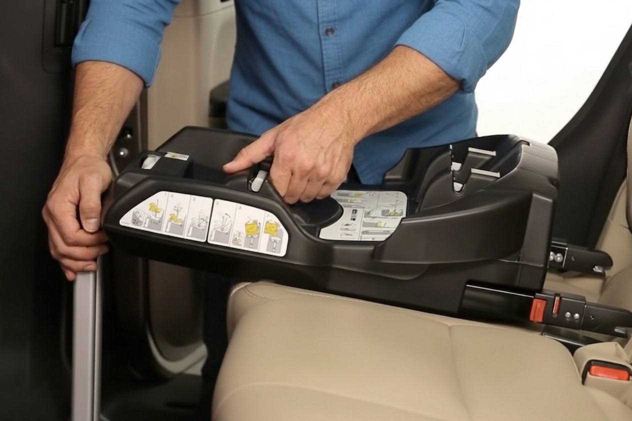 Adult connecting an ISOFIX car-seat connector to a vehicle anchor point