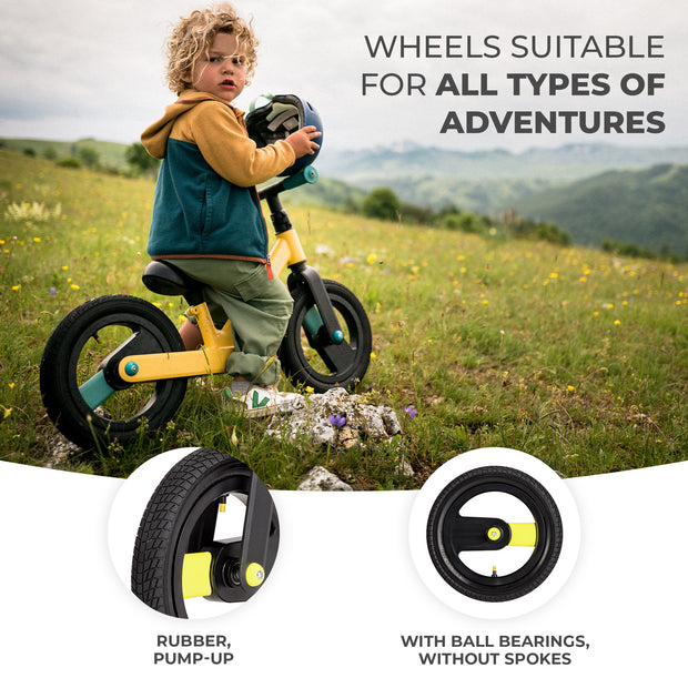 Child with a yellow Kinderkraft GOSWIFT Balance Bike on a grassy field, highlighting rubber, pump-up wheels without spokes.