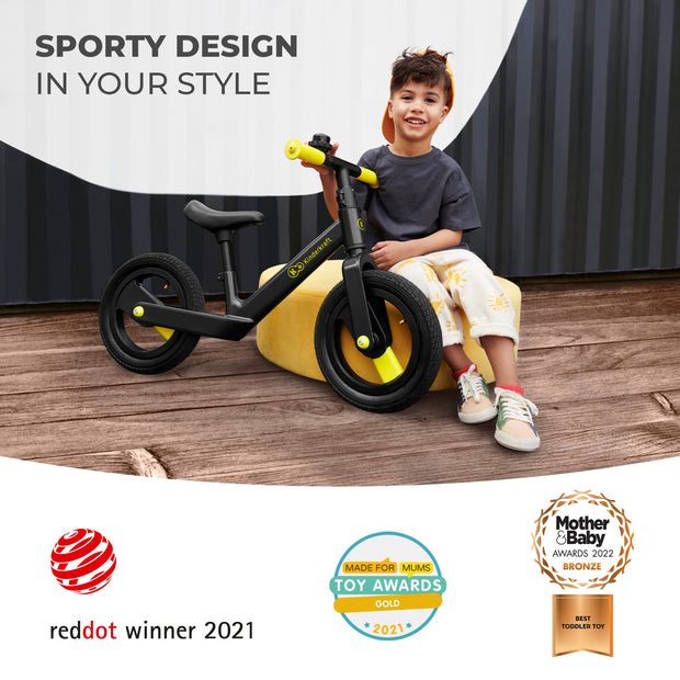 Smiling child sitting on a black Kinderkraft GOSWIFT Balance Bike with sporty design, winner of the Reddot Award 2021.