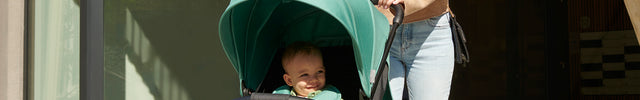 A woman with her baby inside the Kinderkraft Stroller RINE in Juicy Green