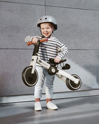 A Little Kid holding the Kinderkraft Balance Bike 4TRIKE
