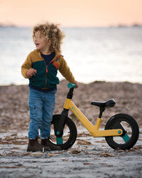 A young boy next to his Kinderkraft Balance Bike GOSWIFT