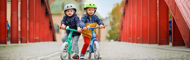 Two kids riding Kinderkraft Balance bikes RAPID side by side.