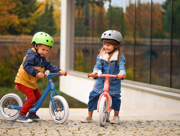 Two toddlers playing with their Kinderkraft Balance Bikes RAPID
