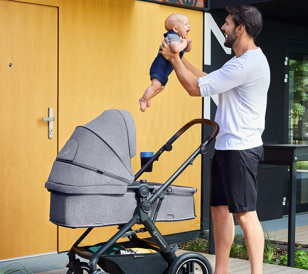 A smiling father taking out his baby from the Kinderkraft Travel System B-TOUR