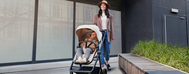 An elegant woman with her baby inside the Kinderkraft Travel System NEWLY
