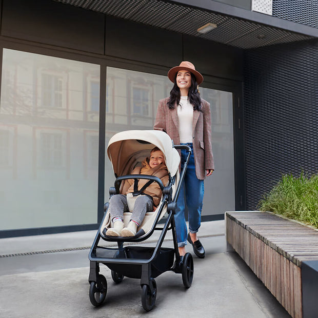 An elegant woman with her baby inside the Kinderkraft Travel System NEWLY
