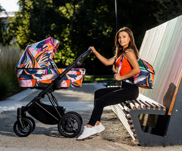 Woman sitting by park with colorful Kunert LAZZIO Stroller and matching bag.