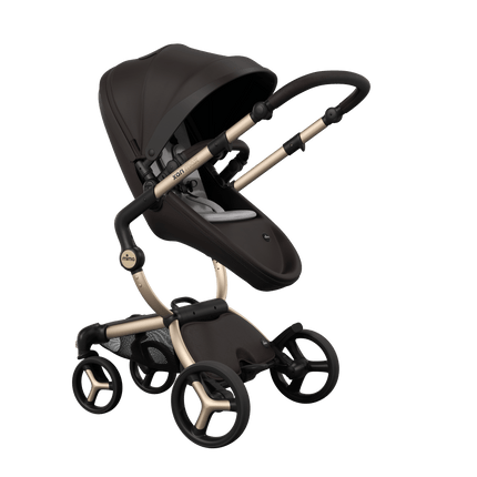 Stylish Mima XARI MAX stroller in chocolate brown with a white pad, showcasing a reversible champagne chassis.