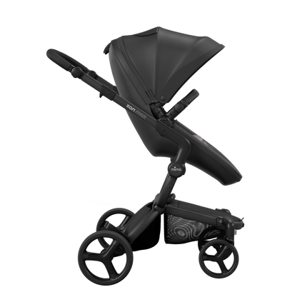 Side view of the Mima XARI MAX stroller, highlighting the black seat and ash sandy beige pad on a durable black chassis.