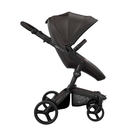 Side view of the Mima XARI MAX stroller, highlighting the chocolate brown seat and sandy beige pad on a durable champagne chassis.