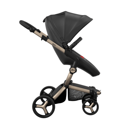 Side view of the Mima XARI MAX stroller, highlighting the black seat and red pad on a durable champagne chassis.