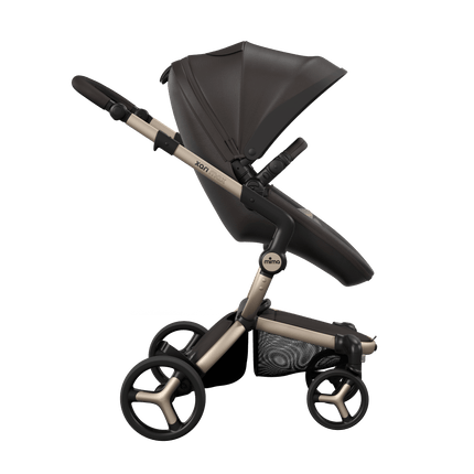 Side view of the Mima XARI MAX stroller, highlighting the chocolate brown seat and sandy beige pad on a durable champagne chassis.