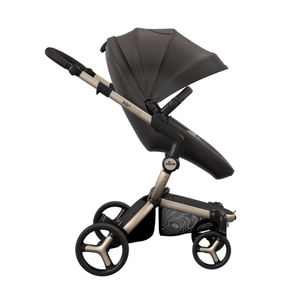 Side view of the Mima XARI MAX stroller, highlighting the chocolate brown seat and sandy beige pad on a durable champagne chassis.