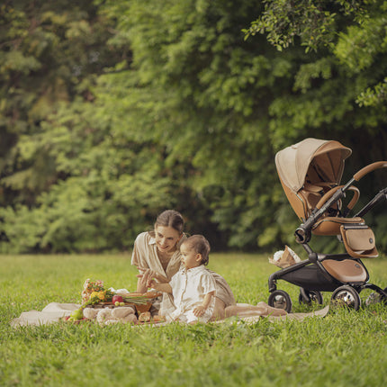 Mima Creo Stroller Mocha in a garden with mom and baby playing.