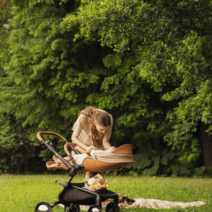 Mima Creo Stroller Mocha in a garden, mom attending to the baby.