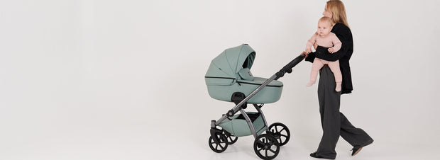 Mother holding baby next to a sleek mint Tutis UNO5+ Eco Leather stroller indoors.