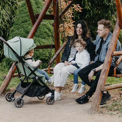 Family sitting and smilling in their baby inside the Coccolle Lightweight Stroller MELIA
