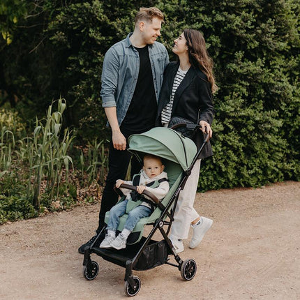 Parents in nature with their baby inside the Coccolle Lightweight Stroller MELIA