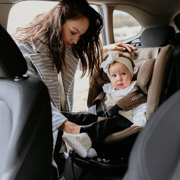 A Little girl sitting inside the Coccolle Rotating Car Seat VELSA iSize in Taupe Brown