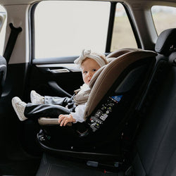 A Little girl sitting inside the Coccolle Rotating Car Seat VELSA iSize in Taupe Brown