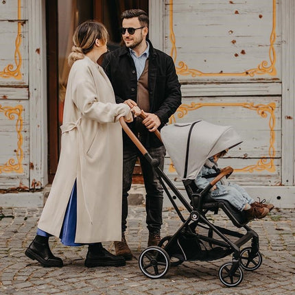 Parents with their kid inside the Coccolle Stroller SALIARA 