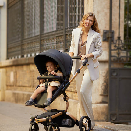 Happy mother with Mima XARI MAX stroller and child outdoors