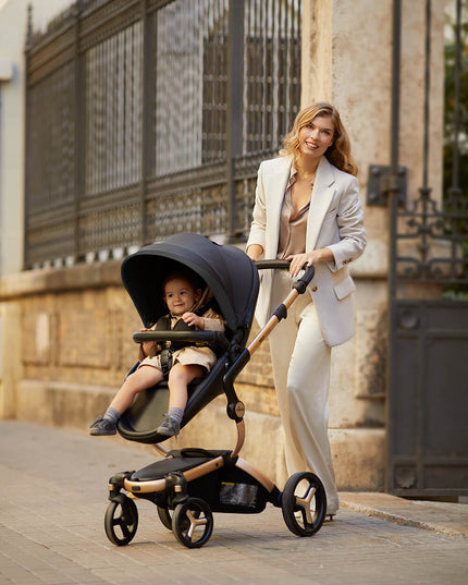 Happy mother with Mima XARI MAX stroller and child outdoors