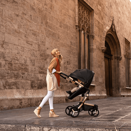 Happy woman walking with Mima XARI MAX stroller by ancient wall