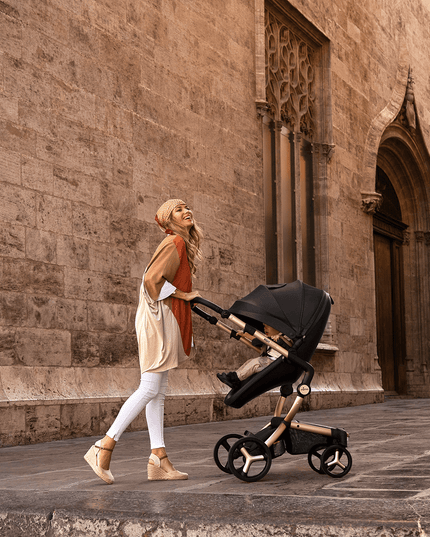 Happy woman walking with Mima XARI MAX stroller by ancient wall