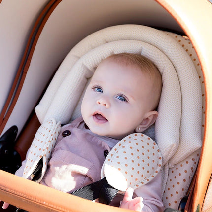 Baby sleeping in Mima MOON high chair with white headrest and pacifier in mouth.