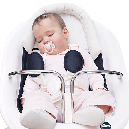 Baby sitting in Mima MOON high chair with white and polka dot headrest, looking awake and alert.