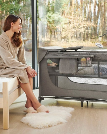 A mother watching her baby inside the Kinderkraft Baby COT JOY 2