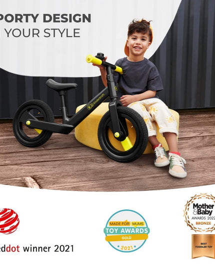 Smiling child sitting on a black Kinderkraft GOSWIFT Balance Bike with sporty design, winner of the Reddot Award 2021.