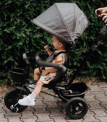 Kinderkraft Tricycle ride in the park with a toddler and a shaded canopy