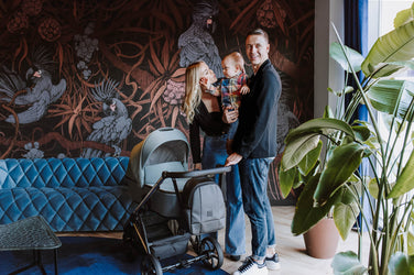 Kunert stroller with a happy family against a decorative wall.