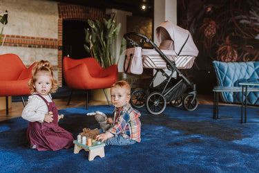 two toddlers playing indoors, vibrant seating in the background and Kunert Stroller IVENTO in the back.