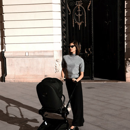 Sleek Mima Creo Stroller Black near a modern building with a parent.