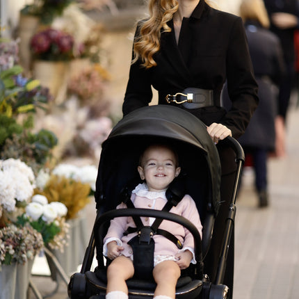 Elegant Mima Creo Stroller Black by a floral arrangement with a parent.