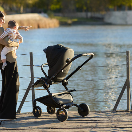 Enjoying a lakeside view with the Mima Creo Stroller Black and a child.