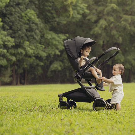 Comfortable Mima Creo Stroller Black in a park with two children.