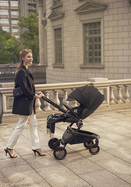 Versatile Mima Creo Stroller Black in a park with a parent and child.