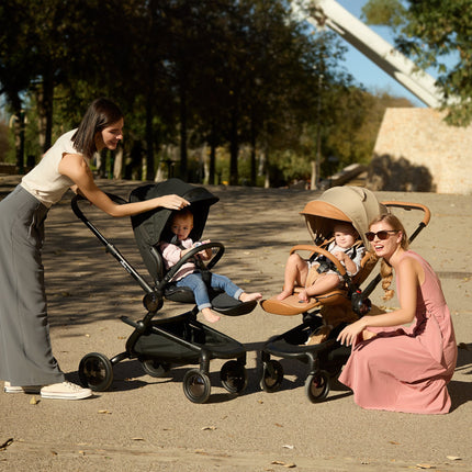  Two parents and their children with Mima Creo Stroller Black and another stroller in the park.