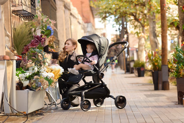 Admiring flowers in the city with the Mima Creo Stroller Black and a child.