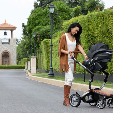 Woman with Mima iZi GO Modular X1 Car Seat on residential street.